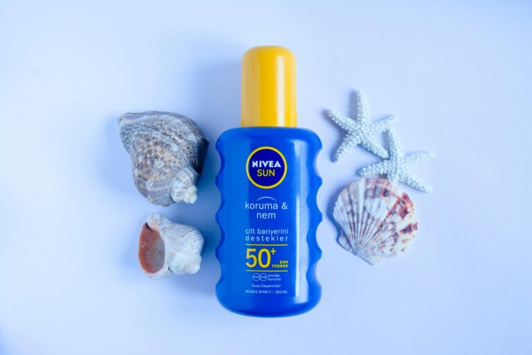 Why Reef-Safe Sunscreen Matters More Than You Think Blue Nivea Sun SPF 50+ sunscreen bottle on white background with seashells and starfish for summer skincare.