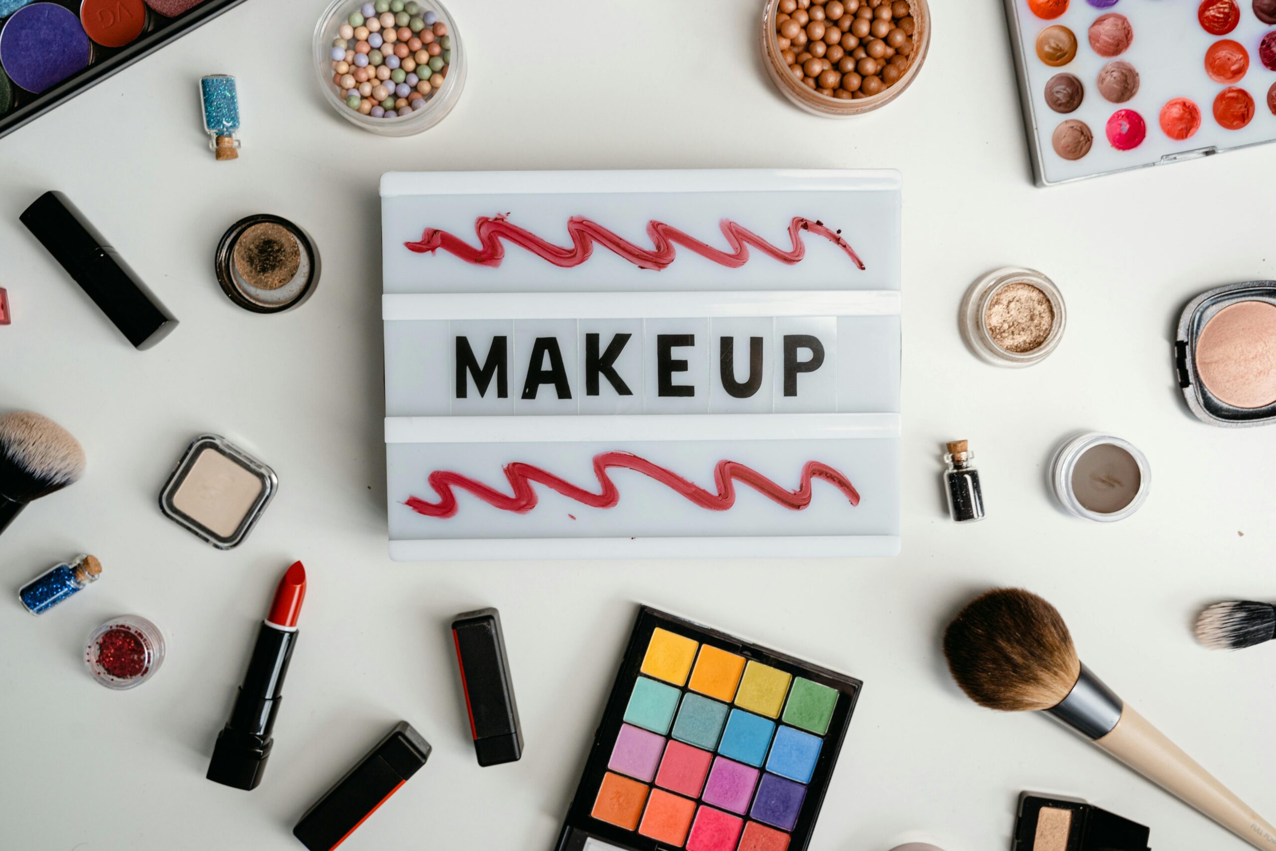 Why You Should Clean Your Makeup Brushes & How to Do It Right Stylish flat lay of various makeup products beautifully arranged around a makeup sign, perfect for beauty concepts.