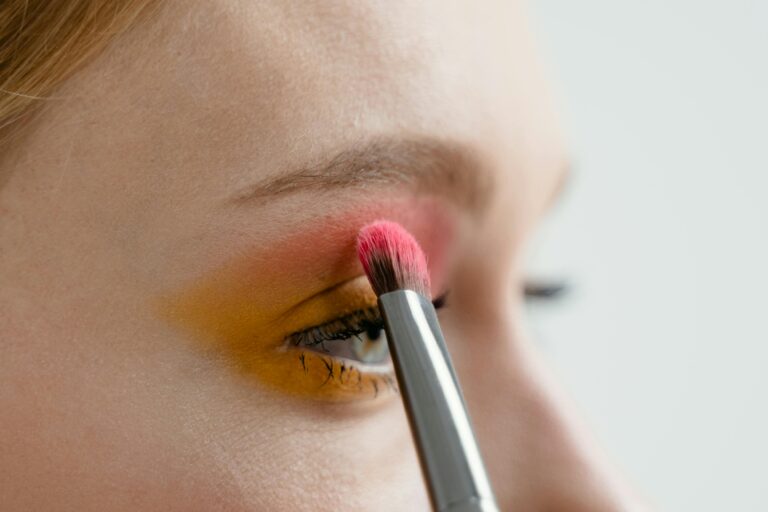 How Eyeshadow Sticks Are Transforming Eye Makeup Application Person applying vibrant eye shadow with a makeup brush for a colorful look.