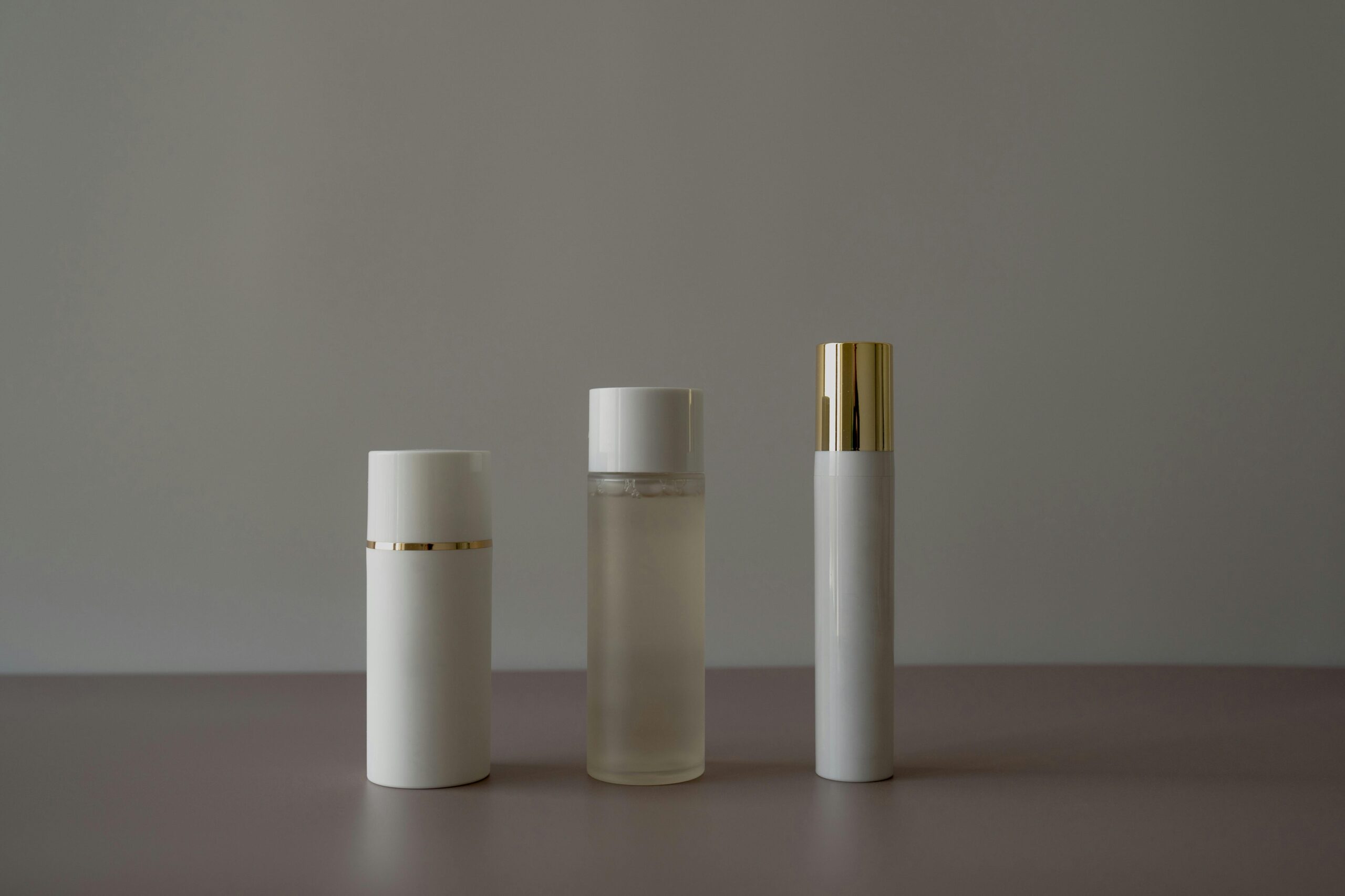 Simple minimalist arrangement of cosmetic bottles on a gray background.